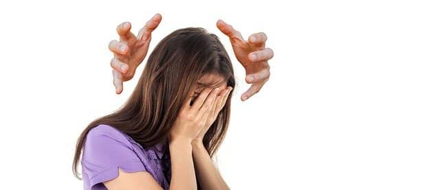 Kopf einer verzweifelten Frau wird von außen von zwei Händen weiter beeinflusst
