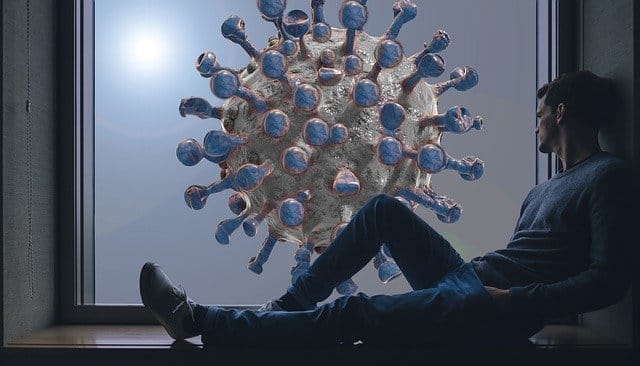 Mann sitzt traurig am Fenster - draußen schwebt ein riesiges Corona-Virus